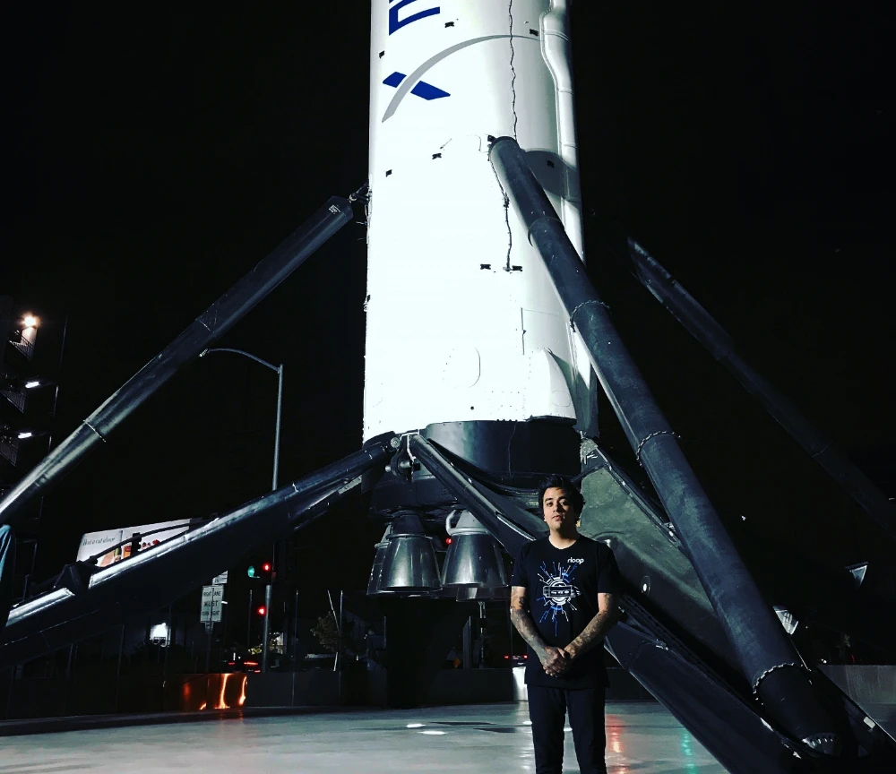 Eros Marcello standing at the base of a landed SpaceX Falcon 9 booster at night